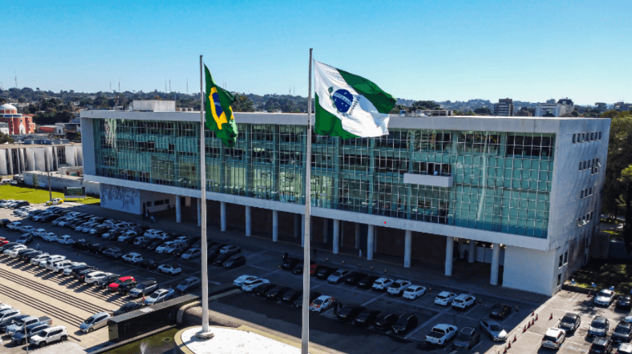 Orçamento estadual: como o dinheiro público é gasto no Paraná Entender para onde vão os recursos do estado é o primeiro passo para exigir transparência e cobrar resultados nas áreas que realmente importam para a sua família Você já parou para pensar de onde vem o asfalto que chega no seu bairro? E a escola que seus filhos frequentam, ou o hospital que atende sua família em uma emergência? Tudo isso só existe porque existe um orçamento público planejado, executado e, acima de tudo, financiado por você, cidadão. O orçamento estadual é, sem exagero, o coração da administração pública. É ele que define as prioridades do governo, que determina quanto será investido em saúde, educação, infraestrutura e segurança. E, em 2026, entender como esse dinheiro é gasto se torna ainda mais importante, porque estamos escolhendo quem vai decidir essas prioridades nos próximos anos. O que é o orçamento estadual e por que ele importa O orçamento estadual é uma lei, aprovada pela Assembleia Legislativa, que estima a receita (o dinheiro que entra) e fixa a despesa (o dinheiro que será gasto) do estado para um ano. Ele prevê quanto será arrecadado com impostos como ICMS e IPVA, além de repasses do governo federal, e como esses recursos serão distribuídos entre as secretarias e os programas de governo. No Paraná, o orçamento anual ultrapassa dezenas de bilhões de reais. Esse dinheiro é investido em: Saúde: Hospitais, UPAs, atendimento básico e medicamentos. Educação: Escolas estaduais, merenda escolar, universidades e tecnologia. Infraestrutura: Obras de pavimentação, saneamento e mobilidade urbana. Segurança: Polícias civil e militar, corpo de bombeiros e sistema prisional. Habitação e desenvolvimento urbano: Programas de moradia popular, regularização fundiária e urbanização. Para mim, Leandro Cazaroto, o orçamento tem que ter endereço Atuo no mercado imobiliário há anos e, nessa trajetória, aprendi uma lição simples: nenhuma obra acontece sem planejamento financeiro. Quando vamos construir um loteamento, precisamos saber exatamente de onde virão os recursos para o asfalto, para a rede de esgoto e para a iluminação pública. O mesmo vale para o orçamento estadual. Não adianta prometer obras grandiosas se o dinheiro não está previsto no orçamento. Não adianta anunciar programas habitacionais se não há dotação orçamentária para executá-los. É por isso que, para mim, a transparência pública começa com um orçamento claro, acessível e bem planejado. “Quando o dinheiro público não tem endereço certo, quem perde é a população que fica esperando por serviços que nunca chegam.” Como acompanhar o gasto público no Paraná Muita gente acredita que acompanhar o orçamento estadual é complicado, coisa de especialista. Mas a verdade é que qualquer cidadão pode e deve fiscalizar como o estado gasta o dinheiro público. Existem ferramentas importantes que ajudam nessa missão: Portal da Transparência do Paraná: Um site onde é possível consultar todas as despesas do estado, desde grandes obras até pequenos contratos. Auditoria e controle interno: Órgãos como o Tribunal de Contas do Estado (TCE-PR) e a Controladoria-Geral do Estado fiscalizam a aplicação dos recursos. Audiências públicas: Antes de ser aprovado, o orçamento é discutido em audiências públicas, onde a população pode contribuir com sugestões e questionamentos. Saber usar essas ferramentas é um ato de cidadania. É a forma de garantir que o dinheiro que sai do seu bolso, por meio dos impostos, esteja sendo aplicado com responsabilidade e eficiência. Os desafios do orçamento paranaense para 2026 O Paraná é um estado com arrecadação robusta, mas também com muitas responsabilidades. Em 2026, os desafios orçamentários incluem: Equilíbrio das contas: Garantir que o estado não gaste mais do que arrecada, mantendo o pagamento do funcionalismo em dia e evitando endividamento excessivo. Investimentos em infraestrutura: O estado precisa de recursos para pavimentar estradas rurais, urbanizar bairros periféricos e ampliar a rede de saneamento básico. Programas habitacionais: O déficit habitacional ainda é uma realidade para milhares de famílias paranaenses, e o orçamento precisa contemplar soluções concretas. Fiscalização e combate ao desperdício: É fundamental direcionar recursos para órgãos de controle que evitem fraudes e desperdícios na gestão pública. Regularização fundiária e o orçamento estadual Um tema que merece atenção especial no orçamento é a regularização fundiária. Milhares de famílias no Paraná vivem em imóveis sem escritura, sem acesso a financiamentos e sem a segurança jurídica de que são, de fato, proprietárias. Regularizar essas áreas exige recursos. Exige mapeamento, levantamento topográfico, análise jurídica e emissão de documentos. E tudo isso precisa estar previsto no orçamento estadual. Sem dotação orçamentária, a regularização não sai do papel, e as famílias continuam vivendo na insegurança. Para mim, que atuo no mercado imobiliário e vejo de perto os efeitos da falta de regularização, destinar recursos para esse fim não é gasto, é investimento social. É dar dignidade a quem construiu sua vida com as próprias mãos. Geração de emprego e transparência: duas faces da mesma moeda Quando o orçamento é bem planejado e executado com transparência, os resultados aparecem em forma de geração de emprego. Obras de infraestrutura, programas habitacionais e investimentos em saneamento movimentam a construção civil, um dos setores que mais empregam no Paraná. Um orçamento transparente também atrai investimentos. Empresas só se instalam em estados onde sabem que os recursos públicos são bem aplicados e que as regras são claras. E mais empregos significam mais arrecadação, criando um ciclo virtuoso de desenvolvimento. O papel do deputado estadual no orçamento Você sabia que o deputado estadual tem um papel fundamental na definição do orçamento? É na Assembleia Legislativa que a proposta enviada pelo governo é analisada, discutida e votada. Os deputados podem apresentar emendas, sugerindo mudanças e direcionando recursos para áreas específicas. Por isso, na hora de escolher seu candidato em 2026, vale a pena perguntar: ele entende de orçamento? Ele sabe como funciona o processo de aprovação? Ele tem compromisso com a transparência e com a aplicação eficiente dos recursos públicos? Um deputado que não domina o orçamento dificilmente conseguirá trazer resultados concretos para sua região. Já um representante que conhece a máquina pública e sabe como funciona a alocação de recursos pode fazer a diferença entre uma obra que sai do papel e uma promessa que fica só no discurso. Faça parte dessa construção O orçamento estadual não é um assunto distante, coisa de gabinete ou de técnicos. Ele impacta diretamente a sua vida: a escola do seu filho, o hospital do seu bairro, a estrada que você usa para trabalhar. Entender como o dinheiro público é gasto é o primeiro passo para cobrar resultados e para exercer a cidadania com consciência. E você, já acessou o Portal da Transparência do Paraná para saber como os recursos estão sendo aplicados na sua cidade? Deixe sua opinião nos comentários abaixo. Sua participação é essencial para construirmos um estado mais justo e transparente. Se você acredita que o Paraná merece mais responsabilidade com o dinheiro público e mais investimentos em áreas como moradia e infraestrutura, compartilhe este artigo com seus amigos e familiares. Vamos ampliar essa conversa! Para acompanhar de perto a nossa caminhada, as propostas e como podemos, juntos, transformar essas ideias em realidade, siga as minhas redes sociais. Sua participação é a força que move essa campanha. Meta Description: Entenda como funciona o orçamento estadual do Paraná, como o dinheiro público é gasto e qual o papel do deputado em 2026. Leandro Cazaroto fala sobre transparência e investimentos. URL Amigável (Slug): orcamento-estadual-parana-dinheiro-publico-leandro-cazaroto Palavras-chave: Principal: orçamento estadual Paraná Secundárias: dinheiro público, transparência pública, eleições 2026 Paraná, pré candidato deputado Paraná, Leandro Cazaroto, mercado imobiliário Paraná, regularização fundiária Links Internos Sugeridos: /artigos/transparencia-publica-parana-2026 /artigos/regularizacao-fundiaria-direito-a-cidade /propostas/infraestrutura-urbana-e-mobilidade Alt Text para Imagens: Foto do candidato: Leandro Cazaroto, pré-candidato a deputado estadual pelo Paraná, com um cenário que remete a planejamento urbano e transparência, destacando seu compromisso com a gestão pública responsável. Imagem ilustrativa: Gráfico representando a distribuição do orçamento estadual entre saúde, educação, infraestrutura e habitação, com destaque para a importância da transparência.